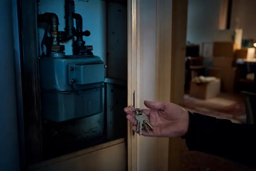 Boîte à compteur de gaz dans l'entrée d'un logement fraîchement libéré, avec des cartons d'emménagement en arrière-plan.